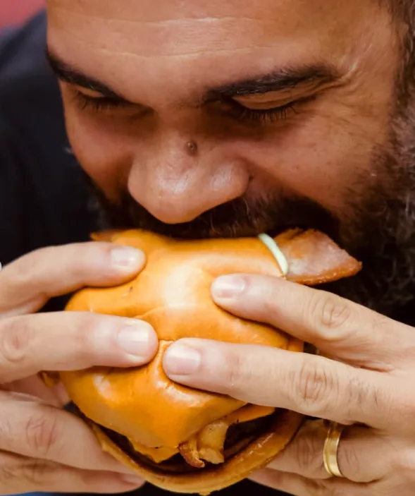 Cliente dando uma mordida em um hambúrguer do Scape Burguer
