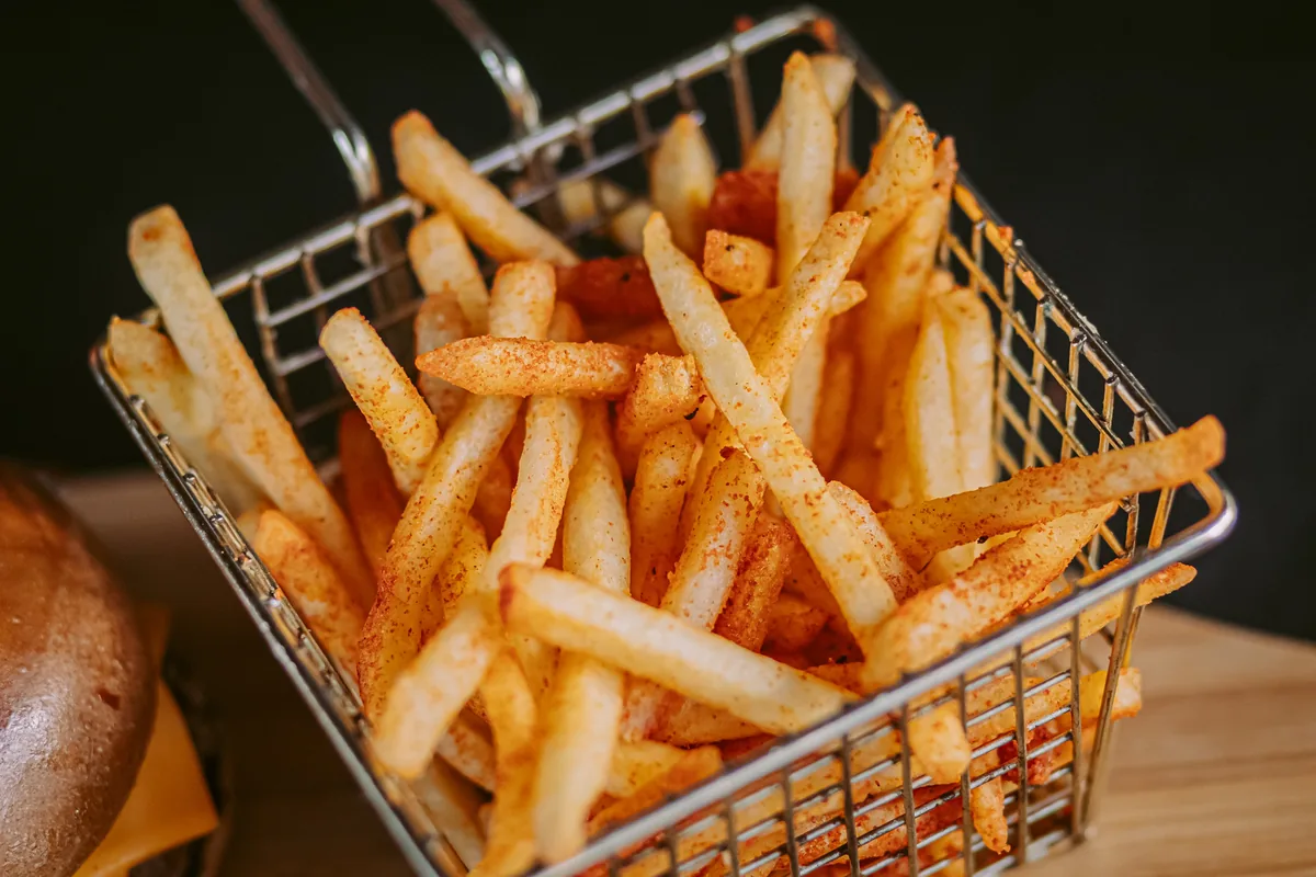 Cesto de batatas fritas temperadas, crocantes e douradas